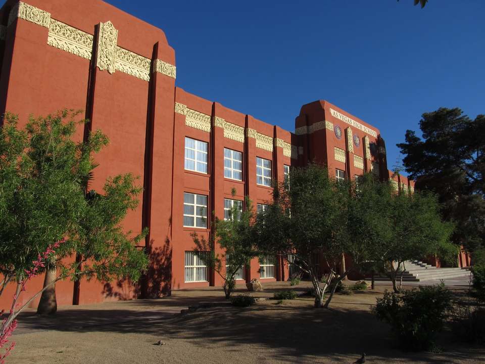 Red brick Art Deco school building with carved trim, trees in front
