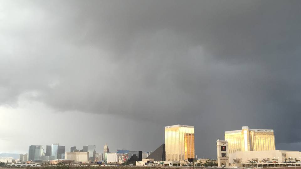 Dark storm clouds and a curtain of rain over the Strip casino towers, gold glass buildings lit by a break in the clouds